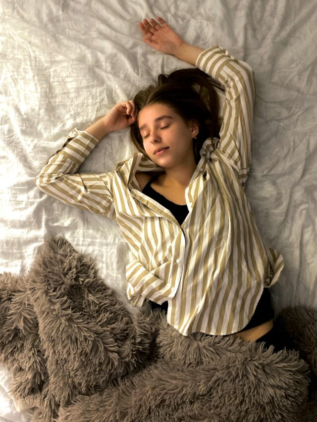 woman in white and black striped long sleeve shirt lying on bed