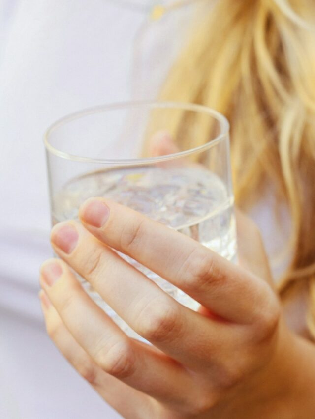 a woman holding a glass of water in her hand