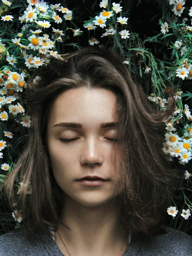woman closing her eyes on white flower